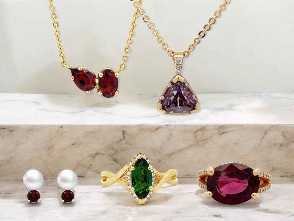 Elegant jewelry collection featuring necklaces, earrings, and rings with vibrant gemstones on marble.