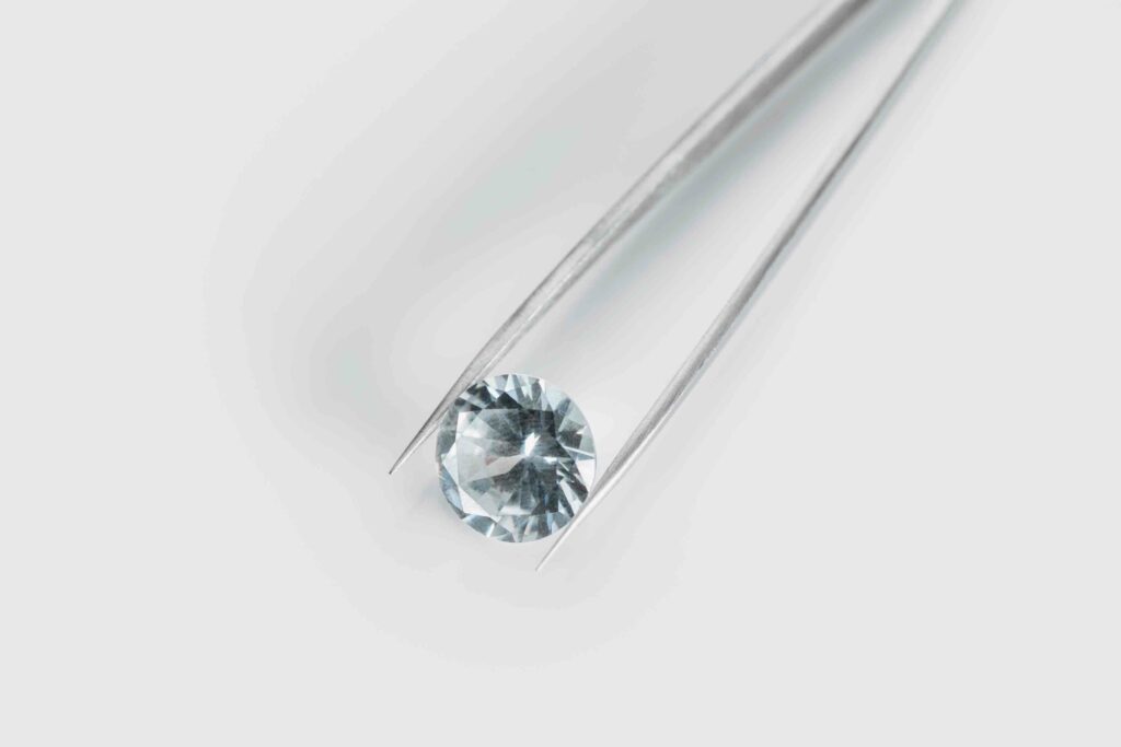 april-birthstone-blog-top-view-of-shiny-diamond-in-tweezers-on-white-back-OPTIMIZED