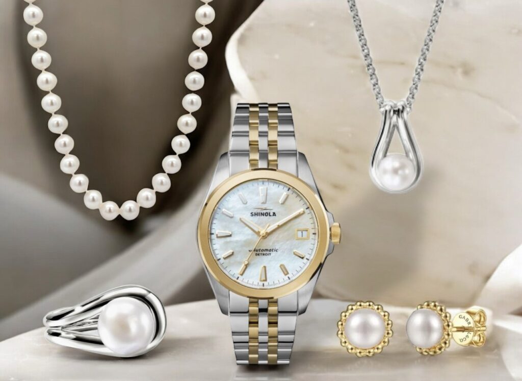 Elegant jewelry collection featuring a Shinola watch, pearl necklace, and earrings on neutral background.