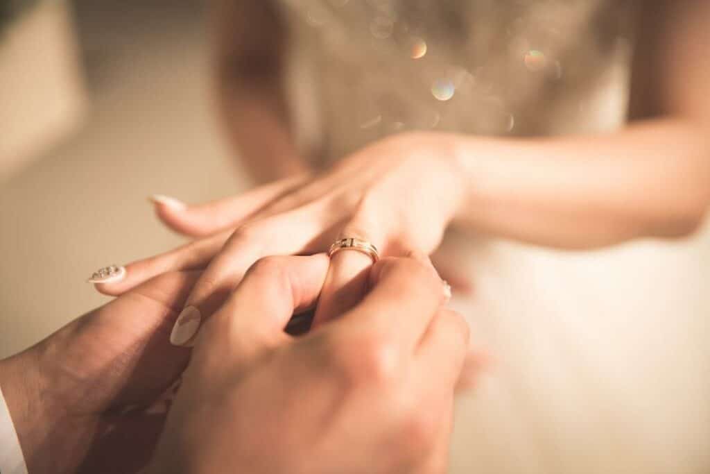 Close-up of man putting wedding ring on brides finger