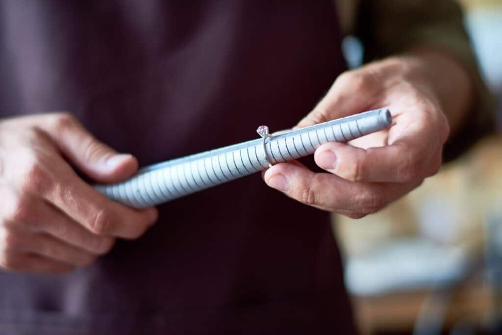 Portrait of unrecognizable jeweler checking ring size with special tool in workshop