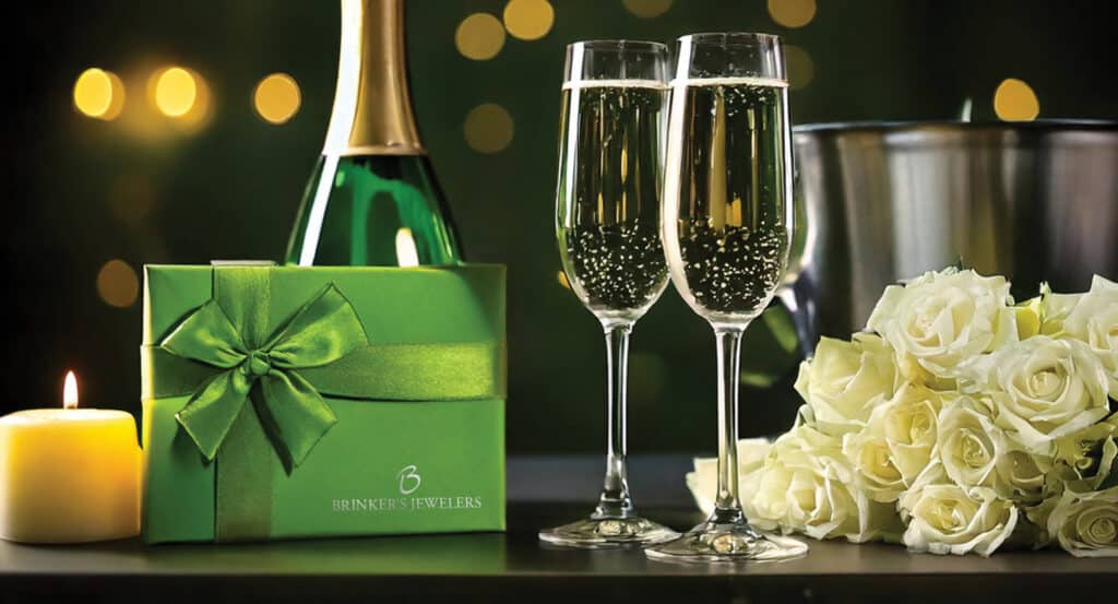 Champagne glasses, a gift box, candle, and roses create a perfect celebration atmosphere.