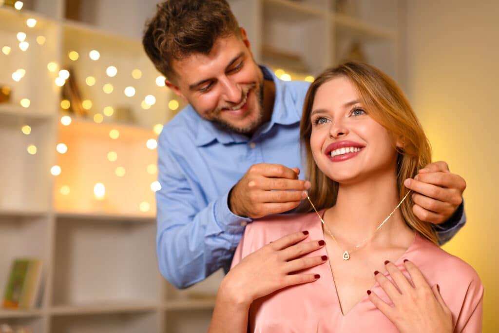 Loving man gifting necklace to delighted woman