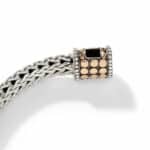 Elegant silver-toned braided bracelet with gold clasp and black stone, perfect for stylish accessories.
