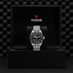 Tudor stainless steel watch in luxury display box; elegant design with black dial and polished bracelet.