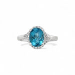 Stunning blue gemstone ring with halo, crafted in white metal, perfect for engagement or style.
