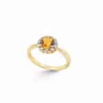 Elegant yellow gold ring with a warm central gemstone and a sparkling diamond halo.