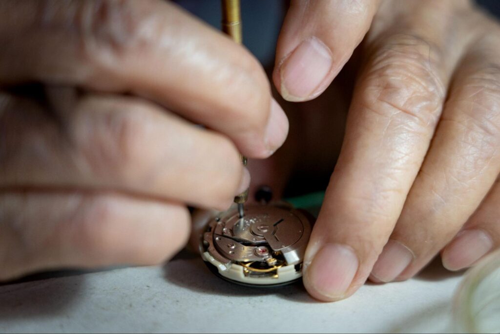Expert watchmaker repairing intricate movement, highlighting the precision of horological craftsmanship.