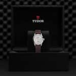 Tudor watch in luxury box, showcasing elegant silver dial and brown leather strap.