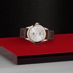 Elegant silver wristwatch on glossy red surface, showcasing luxury craftsmanship and sophisticated design.