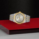 Elegant two-tone stainless steel and gold watch with Roman numerals on a striking red background.