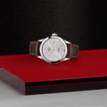 Elegant silver wristwatch on red surface, showcasing luxury craftsmanship and timeless style.