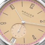Elegant Nomos Glashütte wristwatch with pastel yellow dial, pink chapter ring, and refined design.