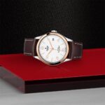 Elegant Tudor watch with rose gold bezel and brown leather strap on a luxurious display.