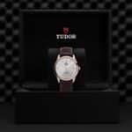 Tudor watch in luxurious black box, featuring leather strap and elegant silver dial.