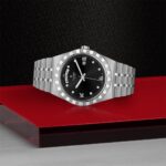 Elegant Tudor watch on red surface, showcasing luxury design and refined craftsmanship.