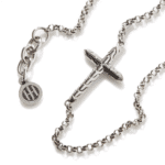 Elegant silver chain necklace with intricate cross pendant and charming emblem. Stylish faith accessory.