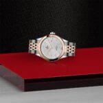 Luxurious rose gold and silver watch on a polished red background, showcasing exquisite craftsmanship.
