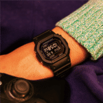 Casio G-Shock watch on wrist near video game controller in relaxed gaming setting.