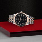 Luxurious Tudor watch with black dial, rose gold accents, and intricate bracelet design.