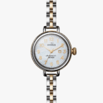 Elegant Shinola watch with mother-of-pearl face, gold accents, and stylish bi-color band.