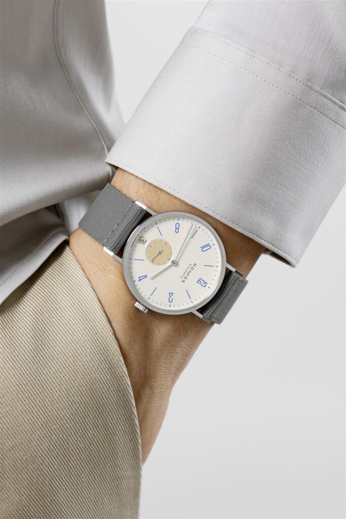 Modern minimalist watch on gray shirt, featuring a sleek design with blue markers.