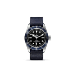 Tudor diving watch with stainless steel case, black dial, blue bezel, and textured fabric strap.