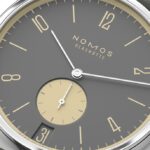 Elegant stainless steel watch with gray dial, yellow accents, and a stylish fabric strap.