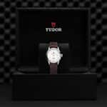 Elegant Tudor watch with stainless steel case and leather strap in luxurious packaging.