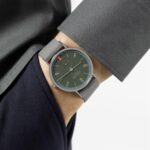 Stylish mans watch with dark green dial and grey strap, perfectly complementing polished attire.