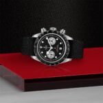 Tudor chronograph watch on red surface, showcasing luxury design and precision craftsmanship.