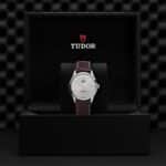 Elegant Tudor watch in a luxury box, featuring a stainless steel case and brown leather strap.