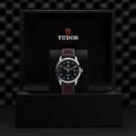 Luxury Tudor watch displayed in elegant black box with brown leather strap and refined design.