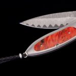 Luxurious damascus steel folding knife with polished wooden handle and decorative leather lanyard.