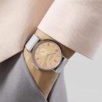 Stylish silver watch with peach dial worn with chic blouse, perfect for casual or formal wear.