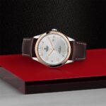 Elegant wristwatch with stainless steel case, rose gold bezel, and leather strap on a luxurious background.