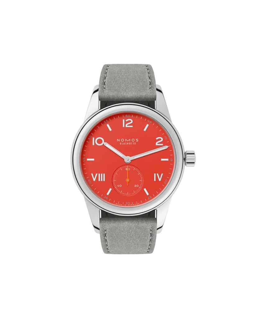 Bold coral-red dial watch by NOMOS Glashütte, featuring sleek design and luxury leather strap.