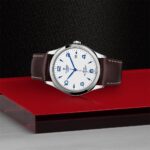 Tudor luxury wristwatch with stainless steel case and leather strap on a striking red platform.