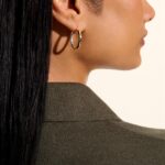 Elegant profile close-up showcasing dual-tone hoop earring and stylish olive-green outfit.
