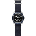 Tudor dive watch featuring a blue bezel, black dial, and navy fabric strap for versatility.