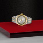 Elegant two-tone watch on a red surface, showcasing luxury design and timeless style.