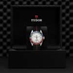 Elegant Tudor watch displayed in a luxurious black box with a sporty blue and red bezel.
