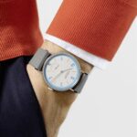 Stylish wristwatch with orange accents, paired with a cozy orange sweater and white shirt.