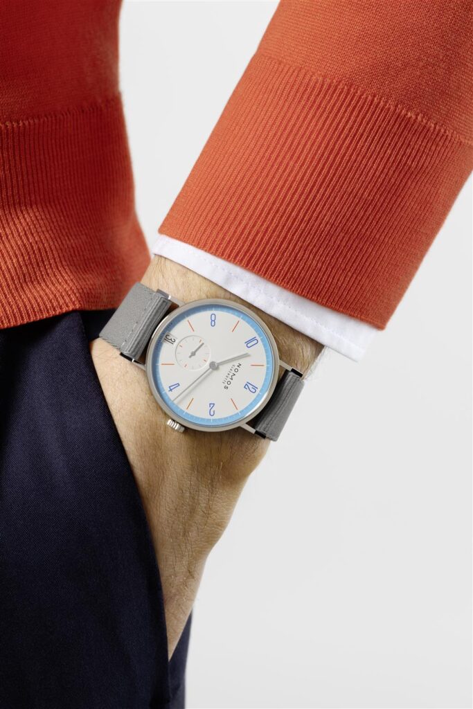 Stylish wristwatch with orange accents, paired with a cozy orange sweater and white shirt.