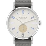 NOMOS Glashütte elegant minimalist watch with cream dial, blue numerals, and gray textile strap.