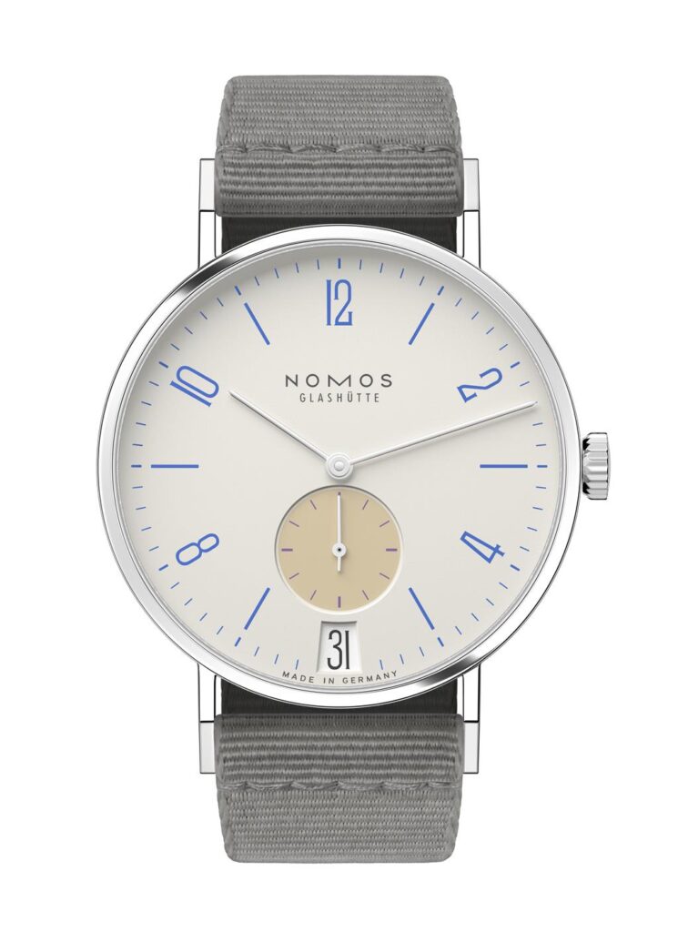 NOMOS Glashütte elegant minimalist watch with cream dial, blue numerals, and gray textile strap.