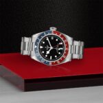 Tudor watch with Pepsi bezel on a striking red and black textured background.