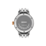Close-up of a Seiko stainless steel wristwatch back with unique engraving and orange crown.