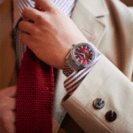 Elegant mans wristwatch with red dial, tailored suit, and coordinated red tie for sophisticated style.