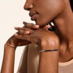 Elegant woman in profile with polished nails and eye-catching modern bracelet.